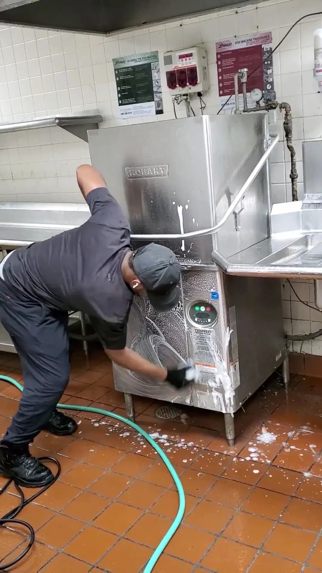 Technician cleaning the exterior of a commercial dishwasher